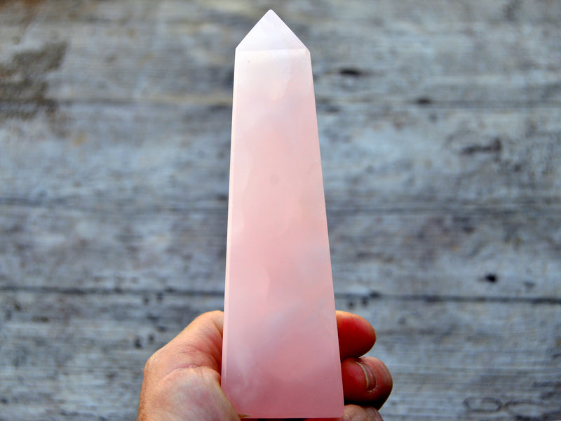 Large mangano calcite obelisk 150mm on hand with wood background