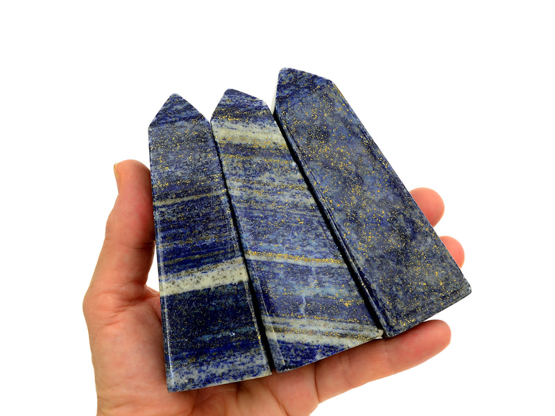 Three lapis lazuli crystal obelisks 90mm on hand with white background