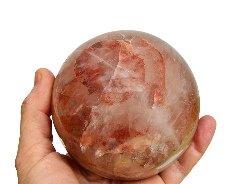 One fire quartz sphere crystal 90mm on hand with white background