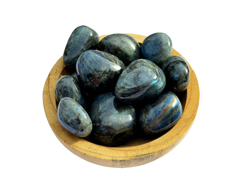 Several large labradorite tumbled crystals inside a wood bowl on white background