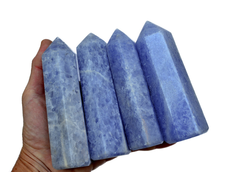 Four blue calcite tower minerals 110mm on hand with white background