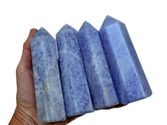 Four blue calcite tower minerals 110mm on hand with white background