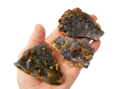 Three purple fluorite clusters on hand with white background