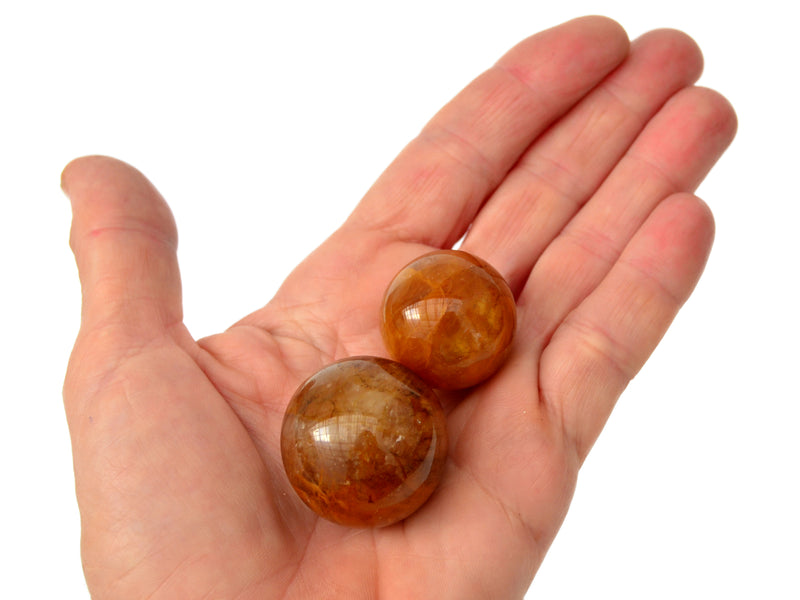 Two yellow hematoid quartz crystal balls 25mm-40mm on hand with white background