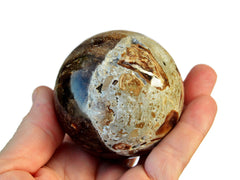 One brown calcite sphere crystal 60mm on hand with white background