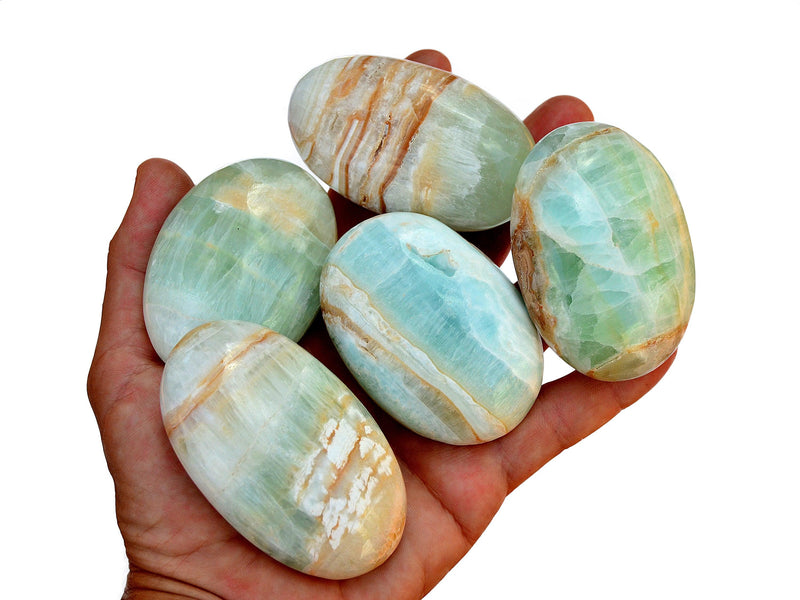 Five blue green caribbean calcite palmstones on hand with white background