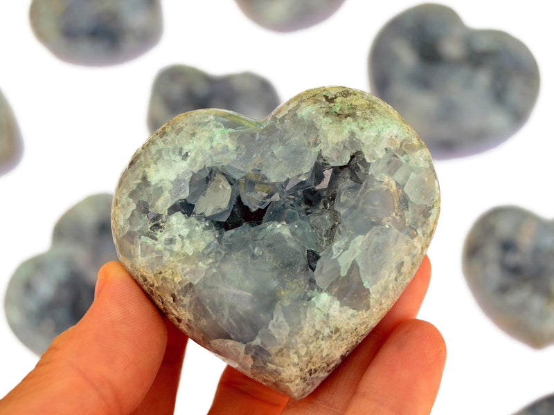One celestite druzy heart on hand with background with some hearts on white
