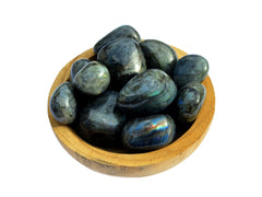 Several chunky labradorite tumbled crystals inside a wood bowl on white background