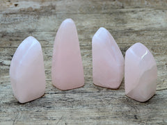 Four pink mangano calcite free forms 80mm-90mm on wood table