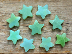 Several green pistachio calcite star shapped minerals 60mm on wood table