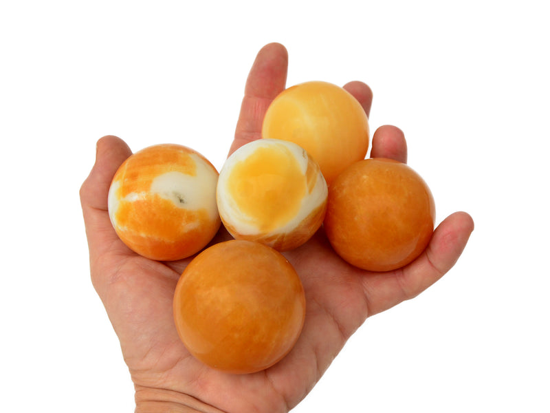 Five orange calcite sphere crystals 45mm on hand with white background