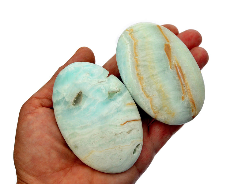 Two large caribbean blue calcite palm stones 75mm-80mm on hand with white background