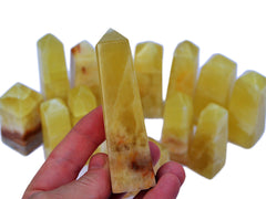 One lemon yellow calcite 90mm on hand with background with some crystals on white
