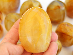 One large golden healer quartz free form mineral on hand with background with some crystals on white