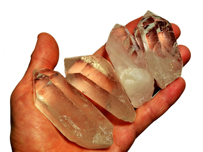 Four raw clear quartz crystal points 70mm-80mm on hand with white background
