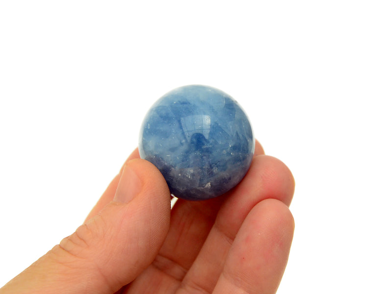One blue calcite sphere 30mm on hand with white background