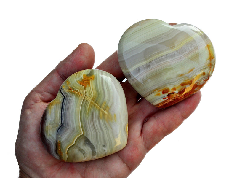 Two pink banded onyx heart stones 65mm-75mm on hand with white background