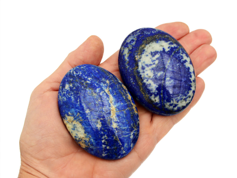 Two large lapis lazuli palm stones on hand with white background