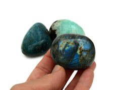 One big labradorite tumbled stone on hand with background with blue apatite and green amazonite