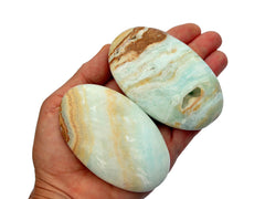 Two large caribbean blue calcite palm stones 75mm-80mm on hand with white background