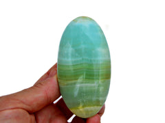 One banded pistachio calcite palm stone 95mm on hand with white background