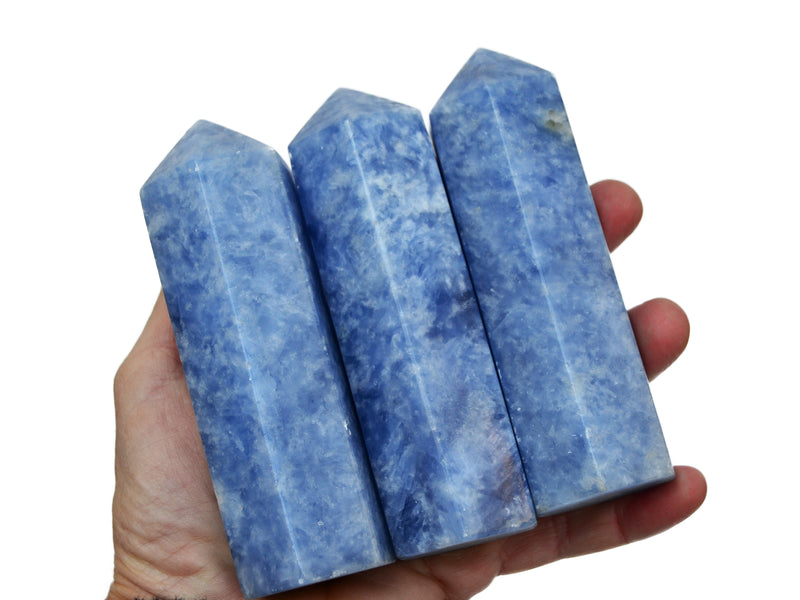 Three large blue calcite tower crystals on hand with white background