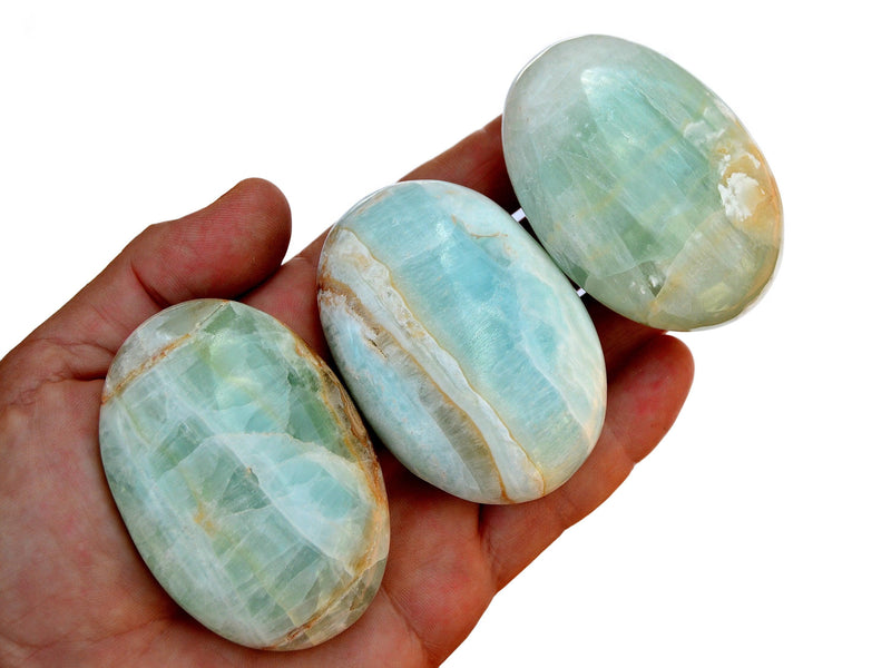 Three blue green caribbean calcite palmstones  50mm-60mm on hand with white background