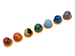 Mini spheres of polychrome jasper, carnelian, yellow septaria, chrysocolla, blue calcite, blue apatite and amethyst crystals forming a diagonal line on wooden bases on a white background.