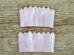 Several pink mangano calcite small faceted points 55mm on wood table