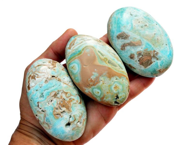 Three blue green aragonite palm stones 80mm on hand with white background