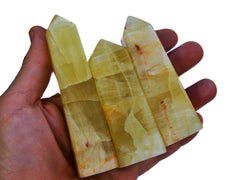 Three lemon calcite crystal points 70mm-140mm on hand with white background