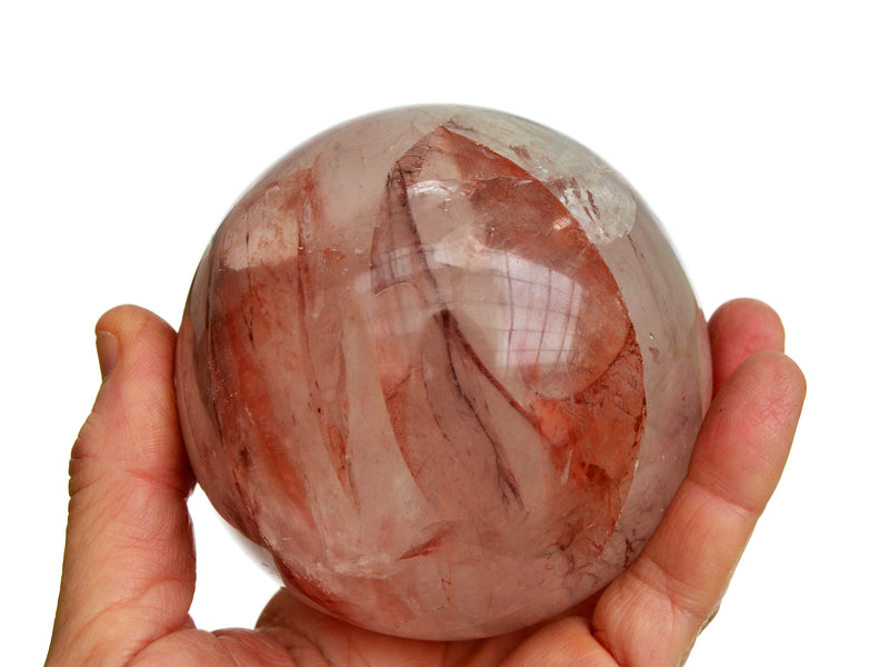 One fire quartz sphere crystal 85mm on hand with white background