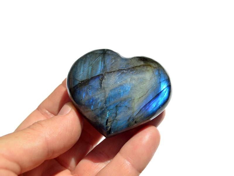 One small blue labradorite heart carving crystal on hand with white background