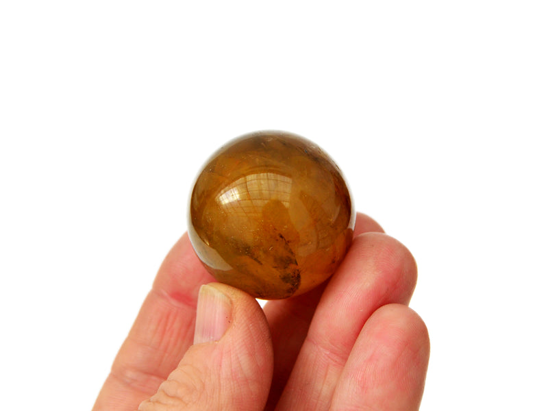 One yellow hematoid quartz sphere 35mm on hand with white background