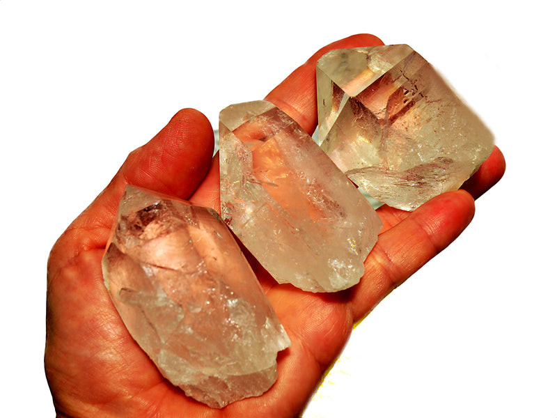Three natural clear quartz points 100g - 150g on hand with white background