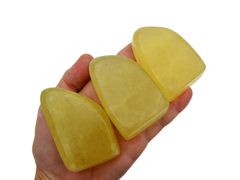 Three lemon calcite free form stones 50mm-70mm on hand with white background