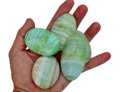 Four pistachio calcite palm stones 65mm-85mm on hand with white background