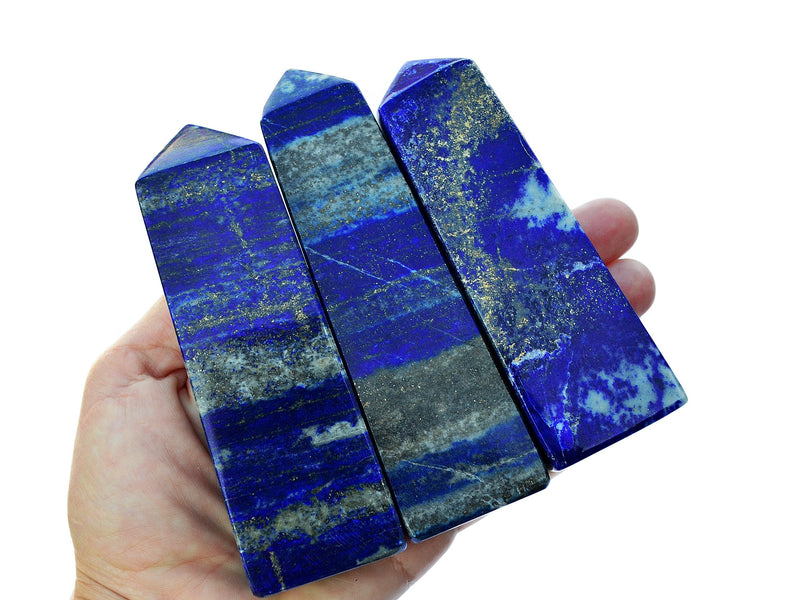 Three large lapis lazuli tower crystals on hand with white background