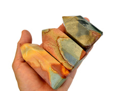 Three short desert jasper faceted points on hand with white background