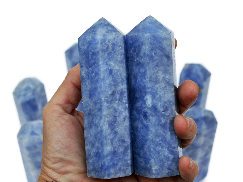 Tow blue calcite towers on hand with background with some stones on white