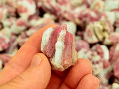 One raw pink tourmaline in matrix 20mm on hand with background with some crystals