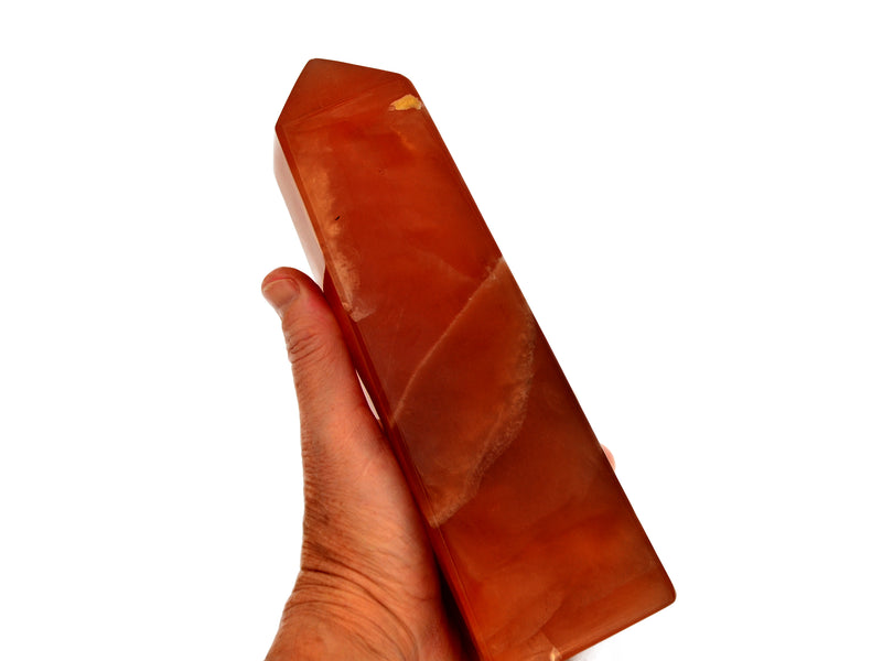 One large honey calcite obelisk stone 190mm on hand with white background