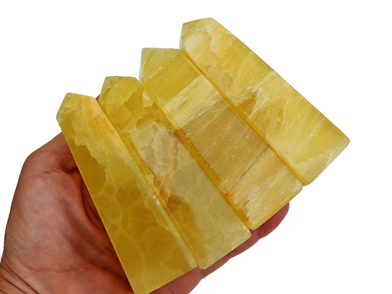 Four lemon yellow calcite 70mm on hand with white background 