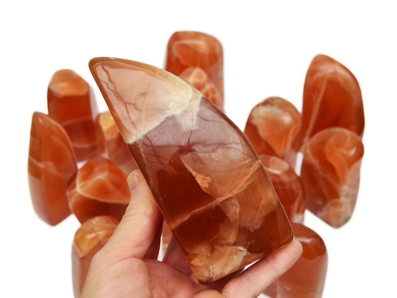 One honey calcite free form 120mm on hand with background with some crystals n white