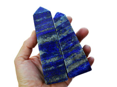 Two blue lapis lazuli crystal towers 110mm-140mm on hand with white background