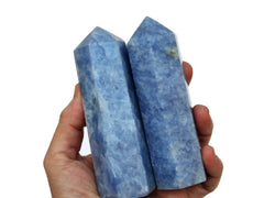 Two large blue calcite towers on hand with white background