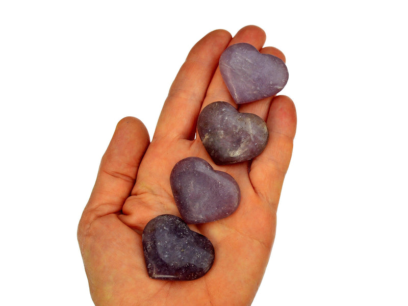 Four lepidolite heart minerals 30mm-35mm on hand with white background