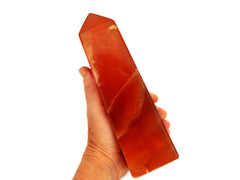 One large honey calcite obelisk crystal 190mm on hand with white background
