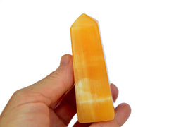 One orange calcite tower 90mm on hand with white background
