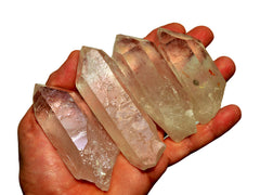 Four natural clear quartz points 70mm-80mm on hand with white background